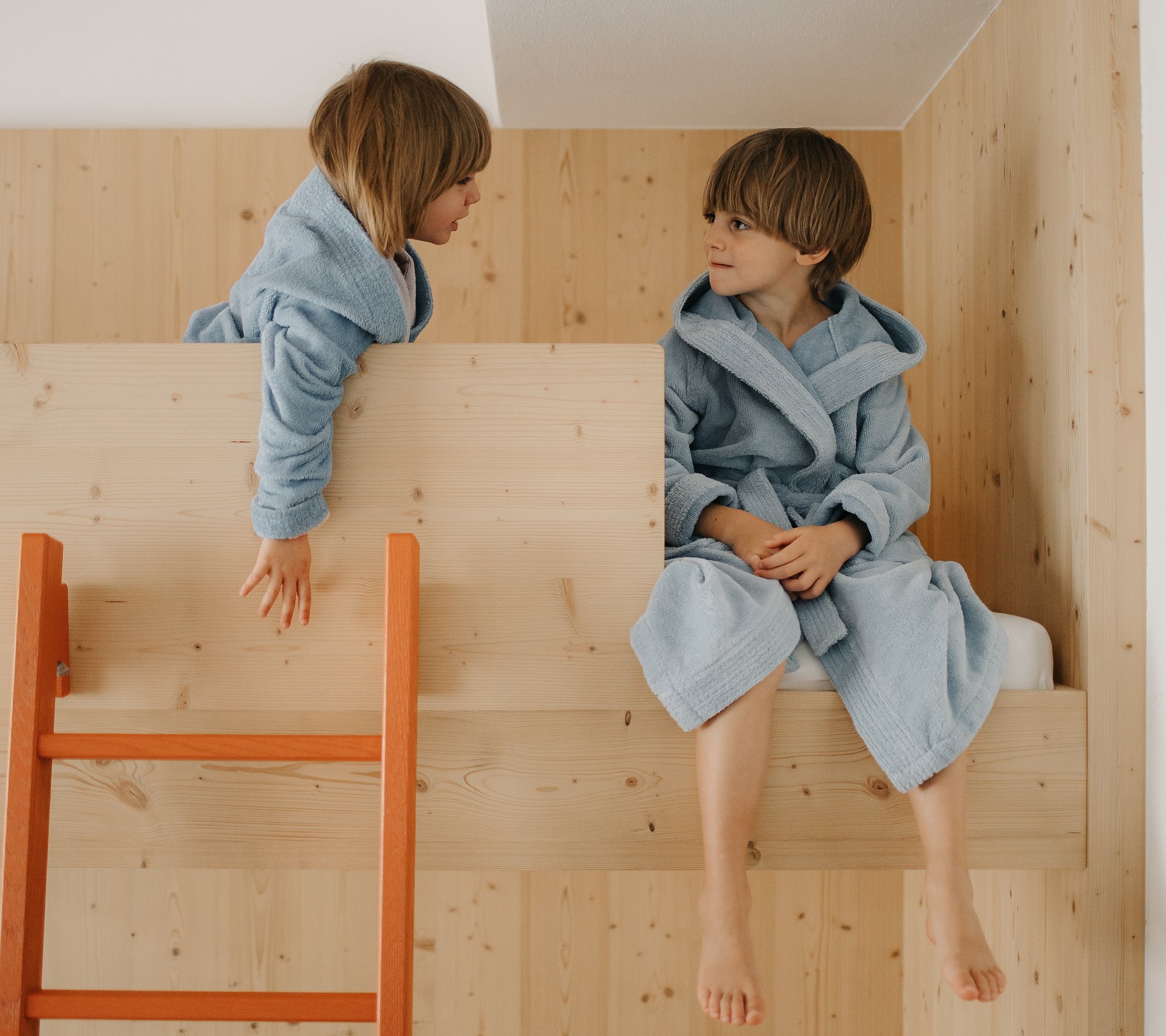 Property detail page - Hotel Rainer Two children in blue bathrobes on a wooden bunk bed