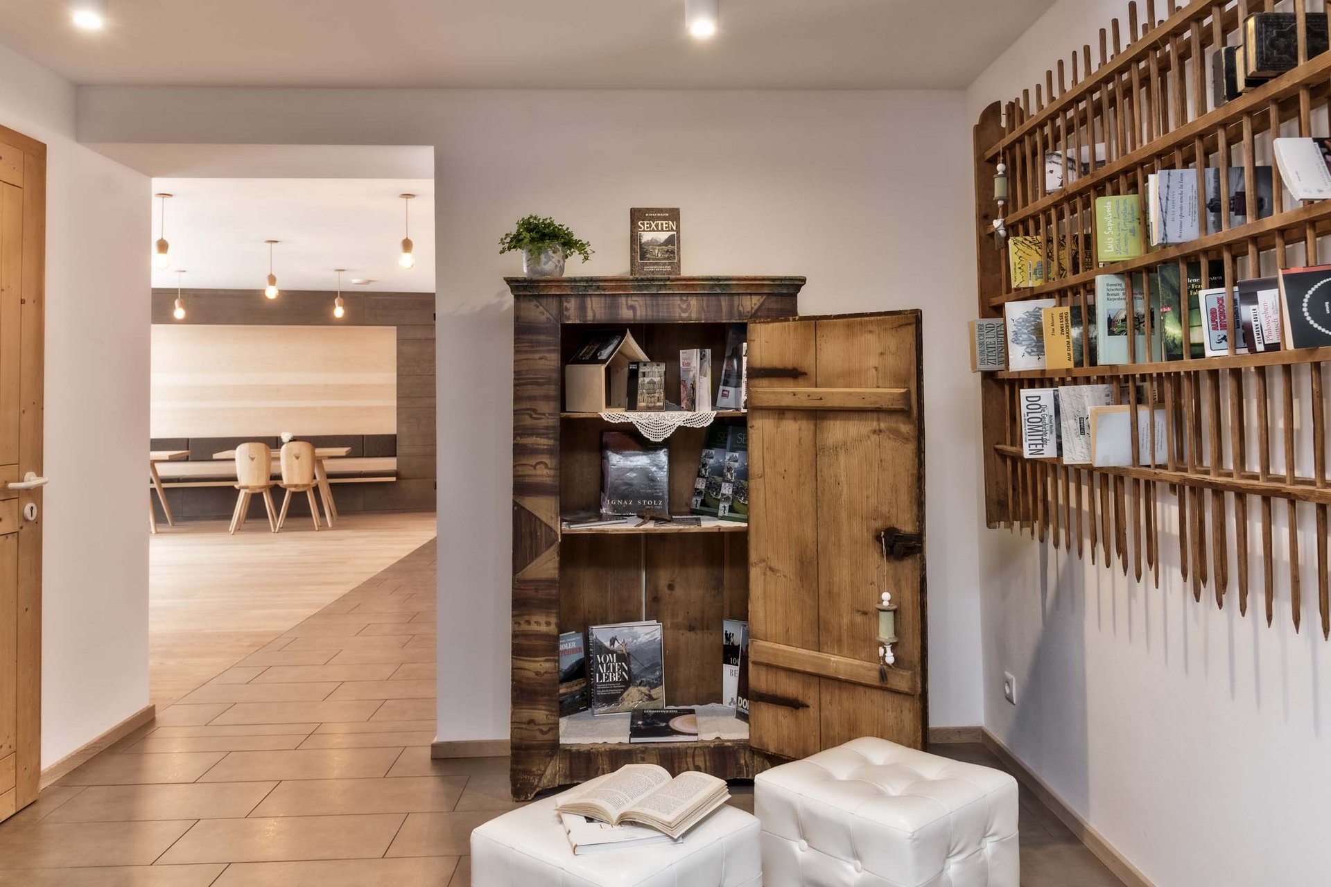 Naturerlebnis in der Villa Rainer Offener Holzschrank mit Büchern in modernem Raum mit weißen Hockern