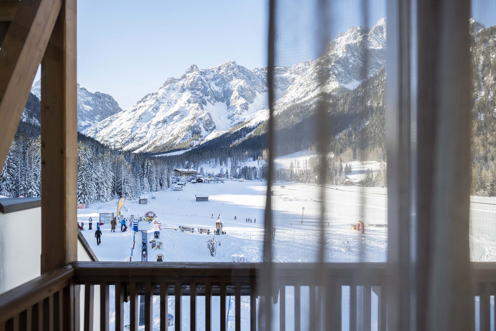 How to get to the Family Resort Rainer View from balcony of snowy mountains with skiers and cabins