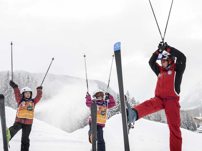 Get to know us! Ski instructor teaching children an exercise in the snow