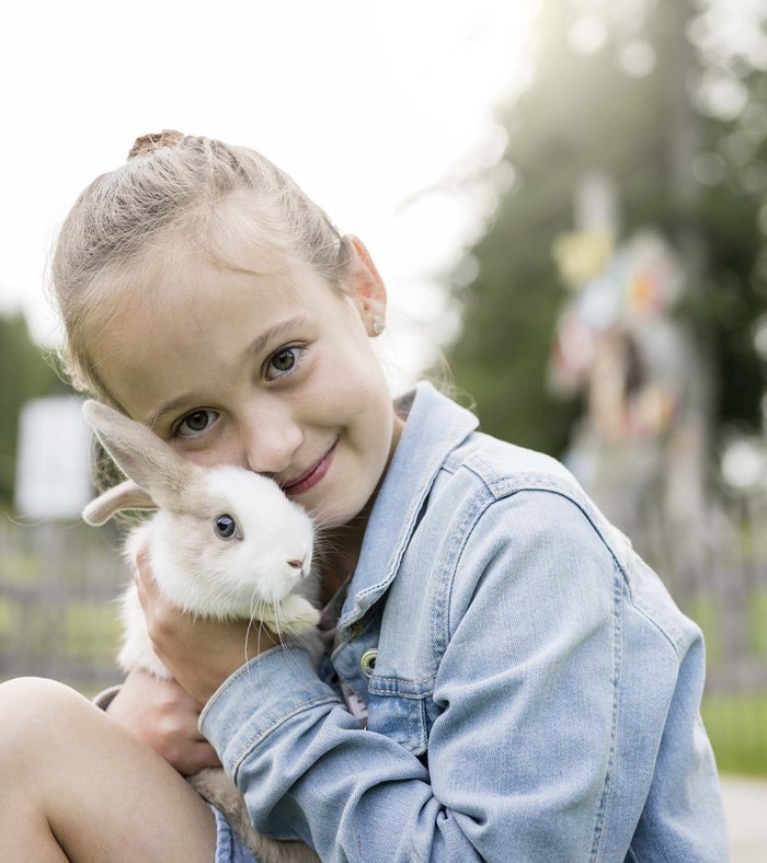 Stay at the Rainer: Family holidays in the Dolomites! Girl hugging a rabbit outdoors in a park