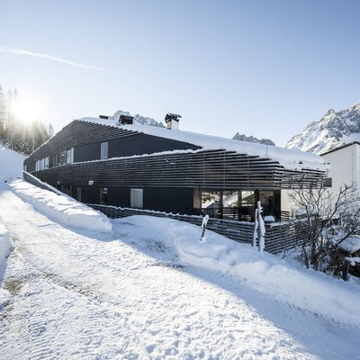 Modernes Gebäude in verschneiter Berglandschaft mit klarem Himmel