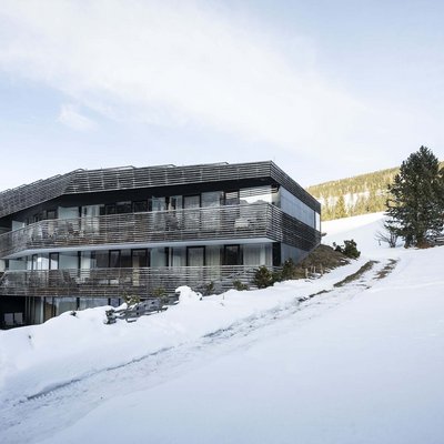 Ihr Familienresort in Südtirol Modernes Gebäude in verschneiter Berglandschaft mit klarem Himmel