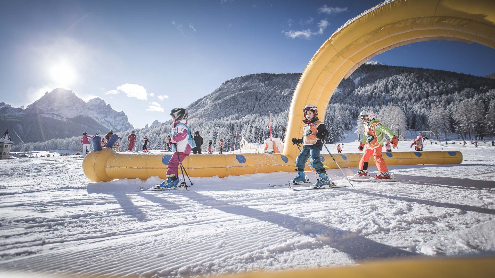Qualche immagine del Rainer Bambini imparano a sciare sotto arco giallo in area sciistica innevata con montagne