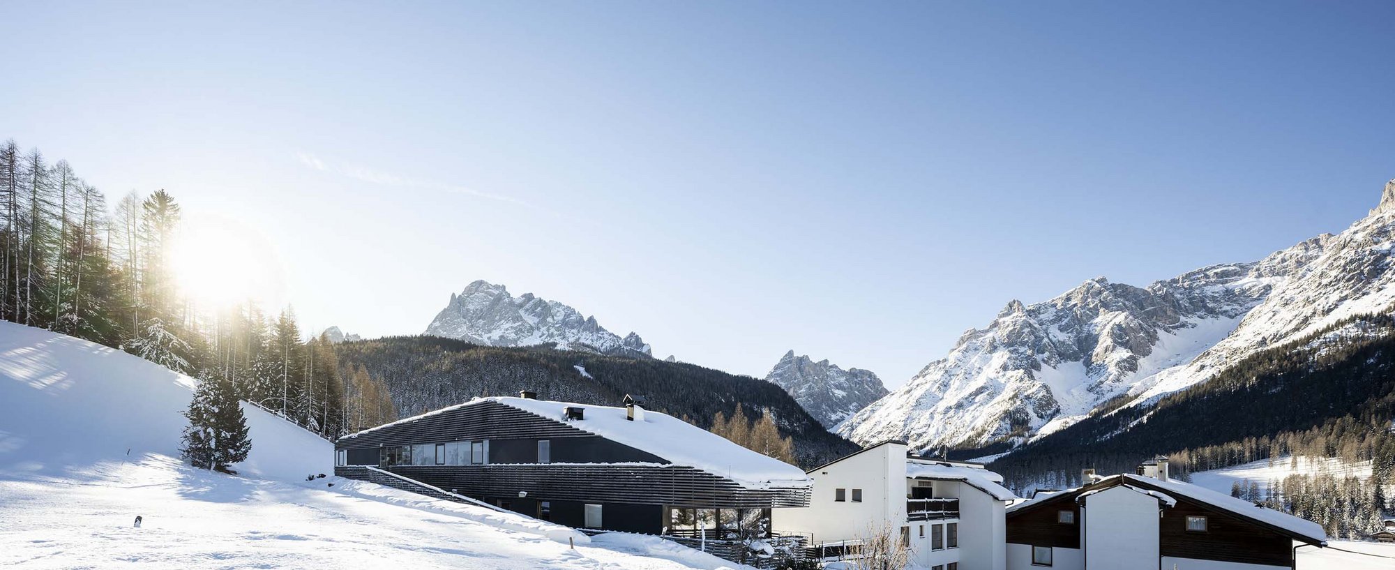 The Residence Königswarte Strata Snow-covered mountain cabins in a sunny alpine landscape with mountain peaks in the background