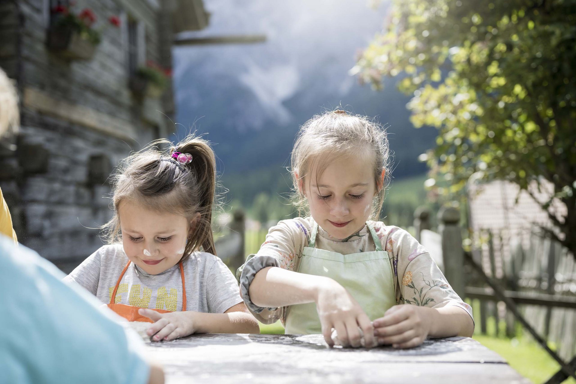How to get to the Family Resort Rainer Two girls kneading dough outside in the garden on a sunny day