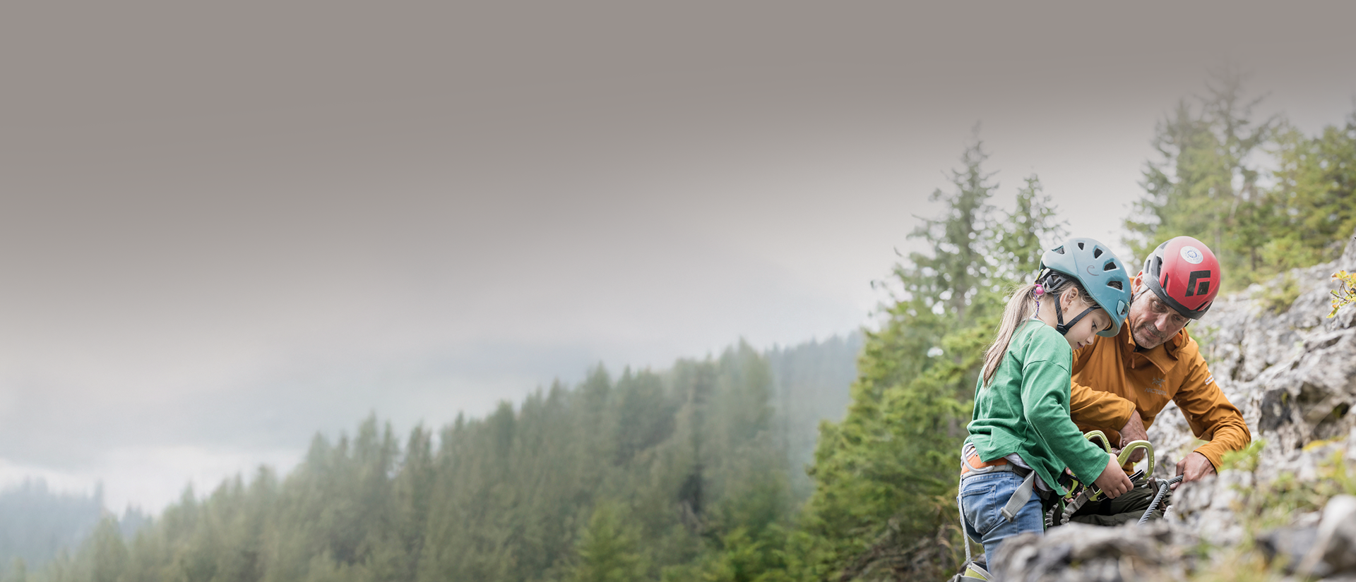 Sexten: a paradise for mountain lovers A child and an adult wearing helmets prepare for rock climbing outdoors